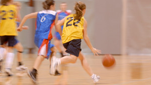 Sports teams playing basketball in a gymnasium