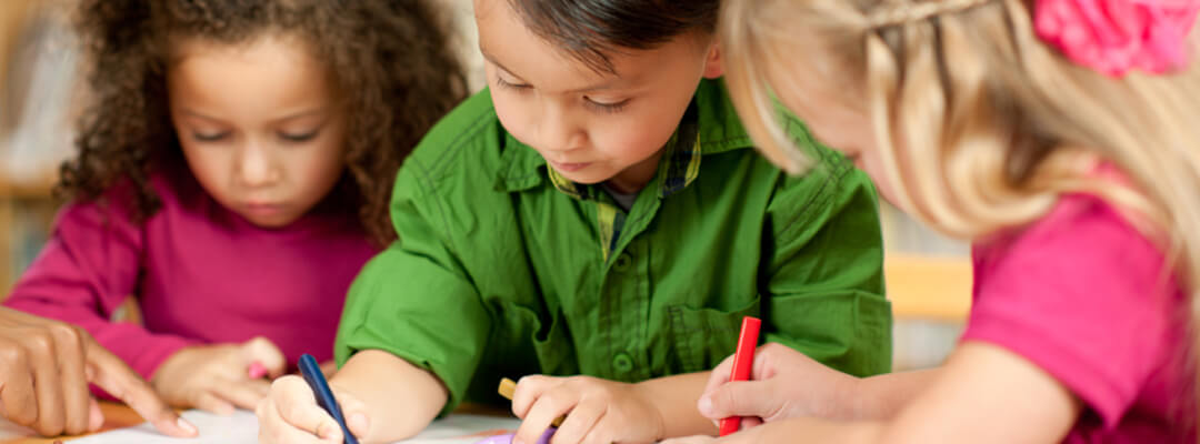 Enfants dessinant dans une salle de classe préscolaire équipée d'un revêtement de sol pour maternelles