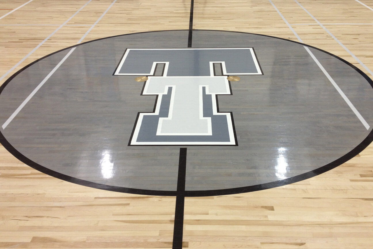 Paint and stain used for logo on hardwood gymnasium sports floor in a school
