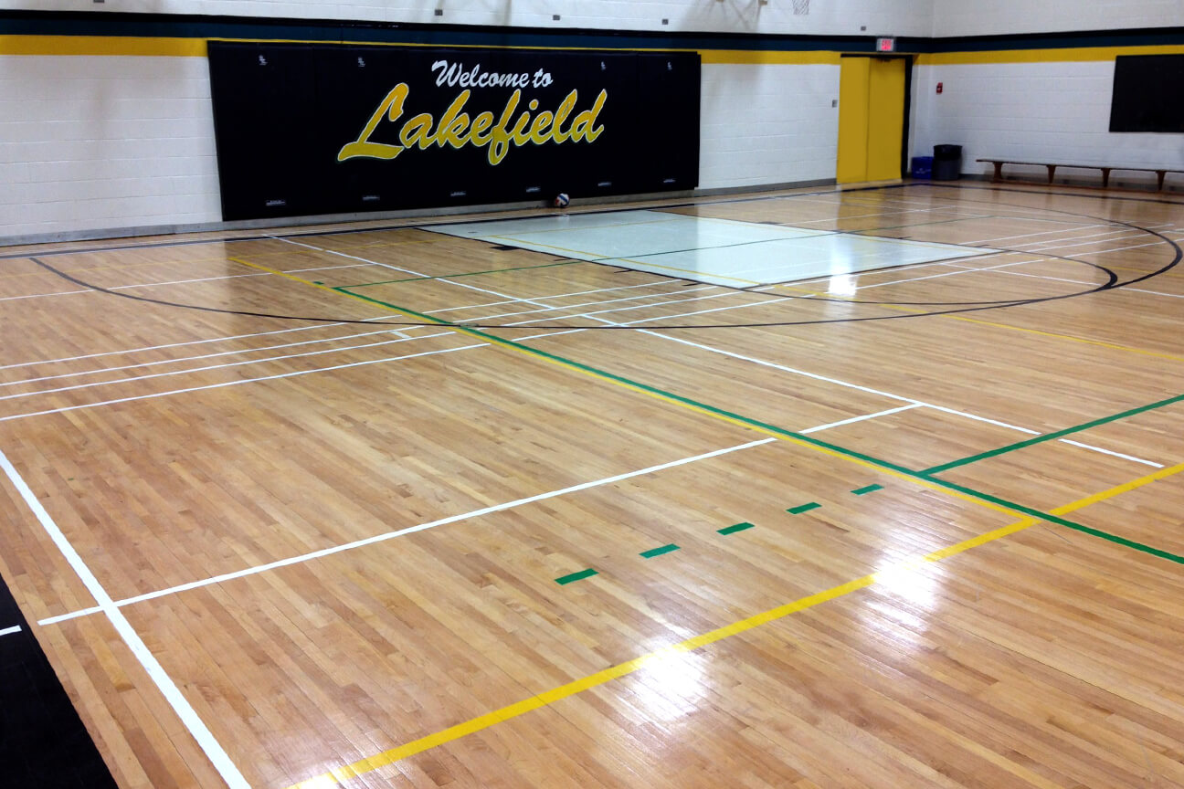 Sablage et finition du plancher de gymnase en bois franc à l'école secondaire Lakefield (Lakefield, Ontario)