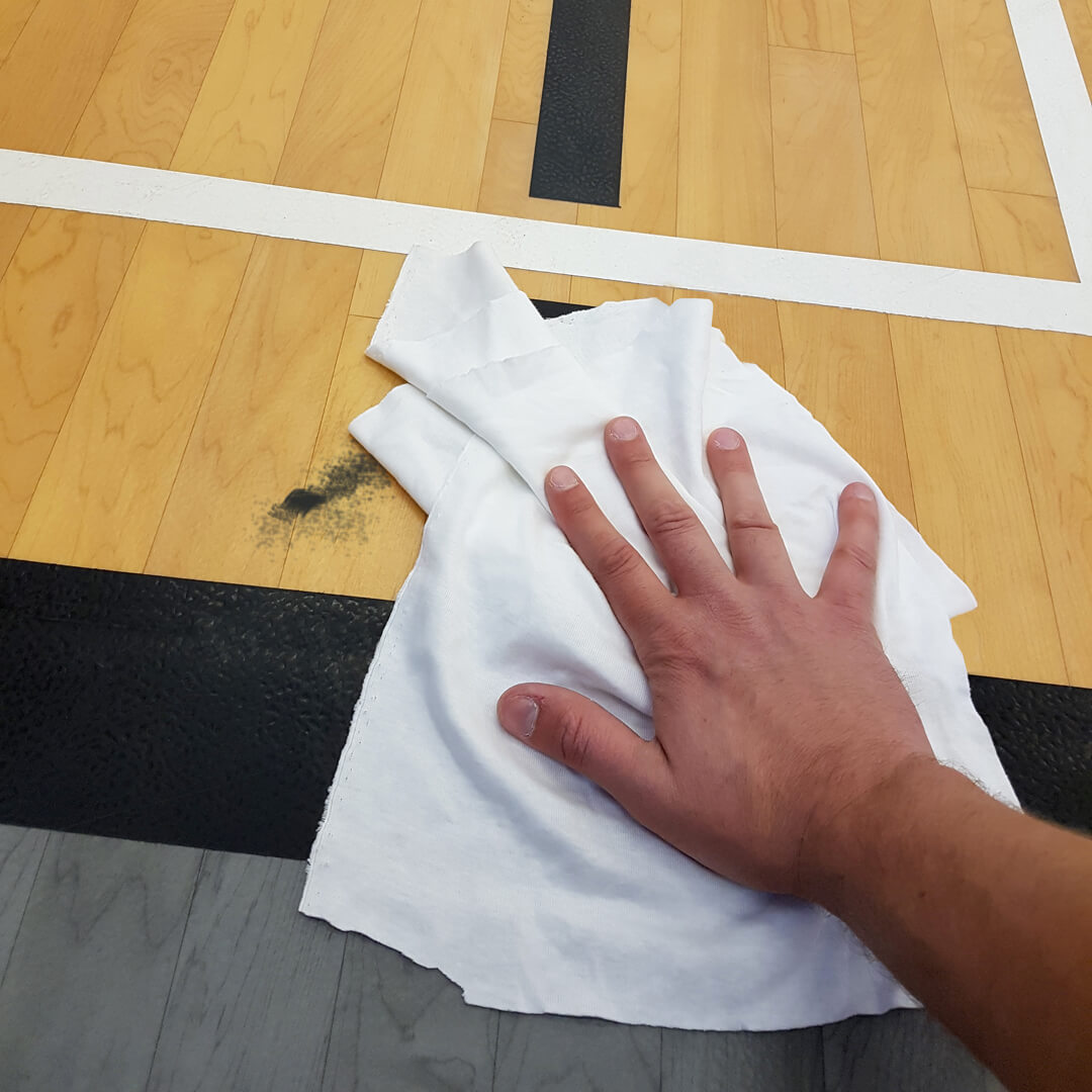 Nettoyage local d'un plancher de gymnase avec un chiffon blanc