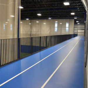 Plancher en vinyle bleu Omnisports installé sur une piste de course intérieure à trois couloirs