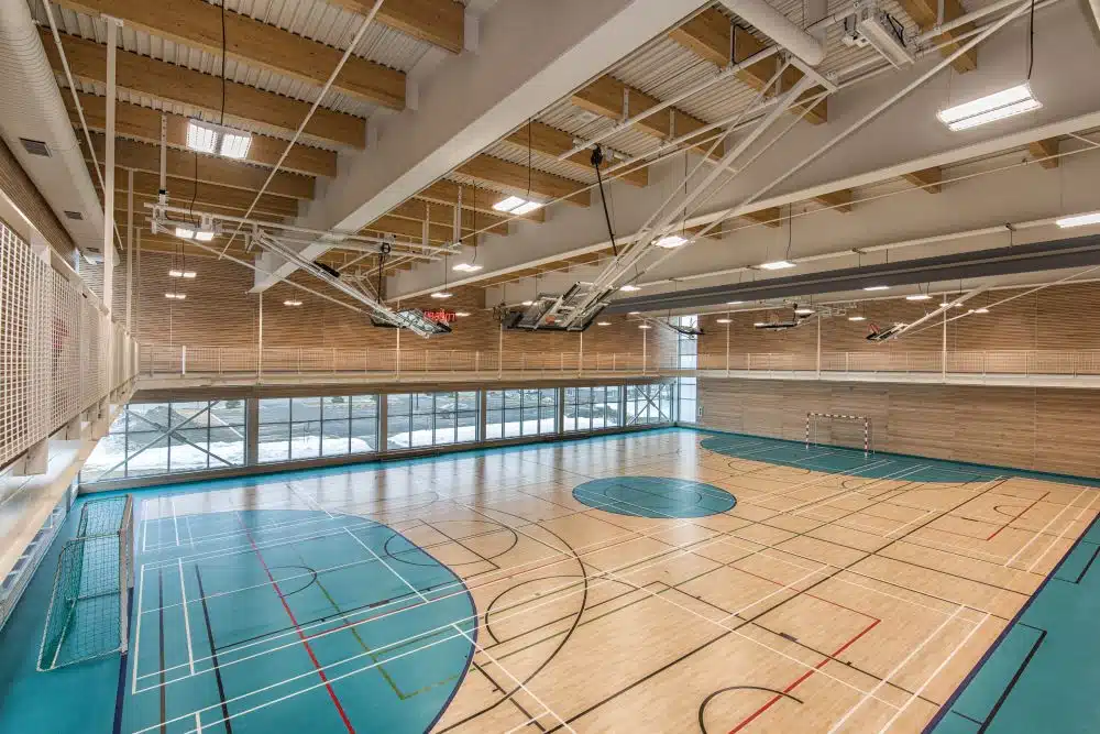 An empty basketball court with light only peering from the windows
